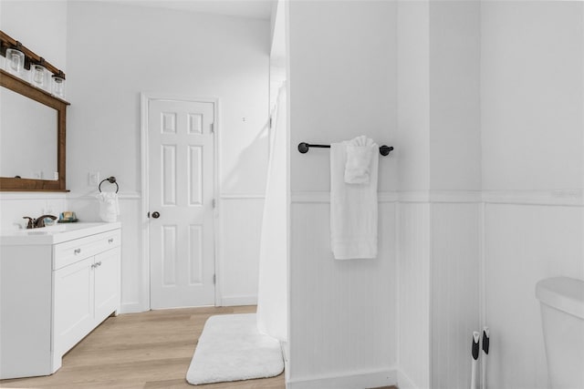 bathroom featuring wood-type flooring, toilet, and vanity