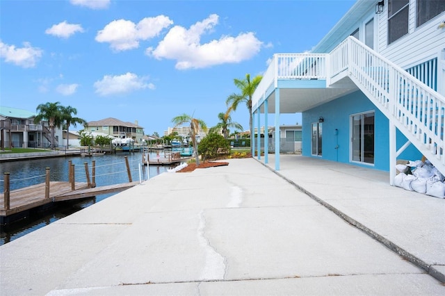 view of dock with stairs, a patio, and a water view