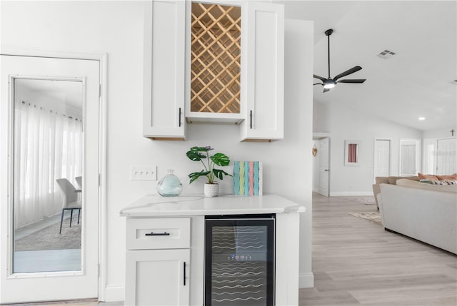 bar featuring wine cooler, a dry bar, lofted ceiling, visible vents, and baseboards