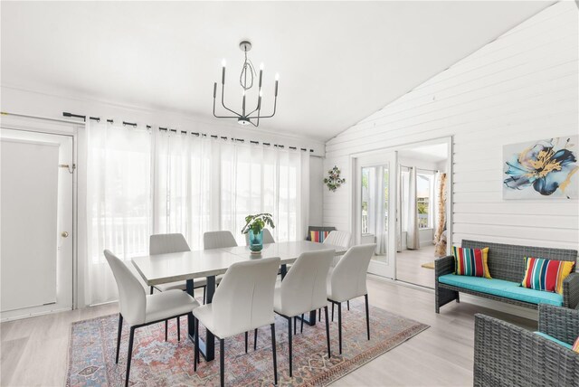 dining area featuring light hardwood / wood-style flooring, lofted ceiling, and an inviting chandelier