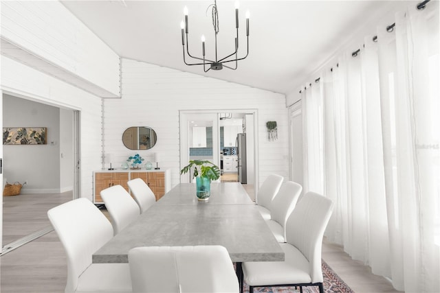 dining room with light hardwood / wood-style floors, a chandelier, and lofted ceiling