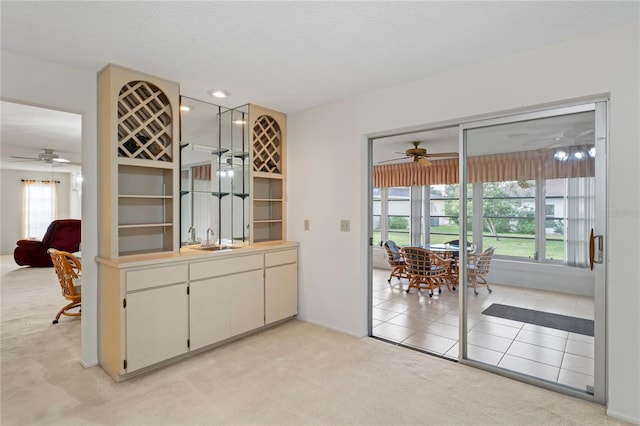 interior space featuring ceiling fan, light colored carpet, sink, and a wealth of natural light