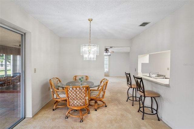 carpeted dining room with ceiling fan with notable chandelier, sink, and a textured ceiling