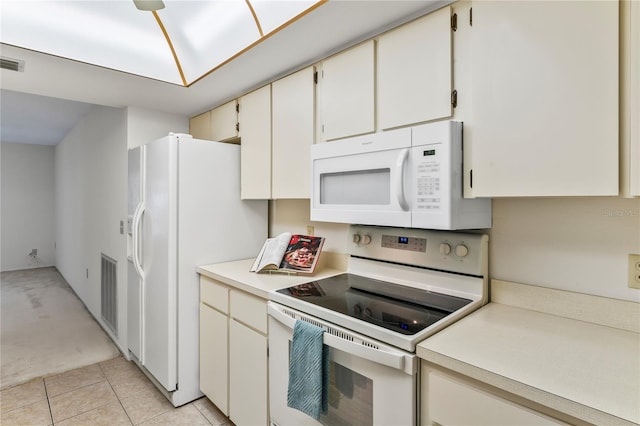 kitchen with white cabinets, light tile patterned floors, and white appliances