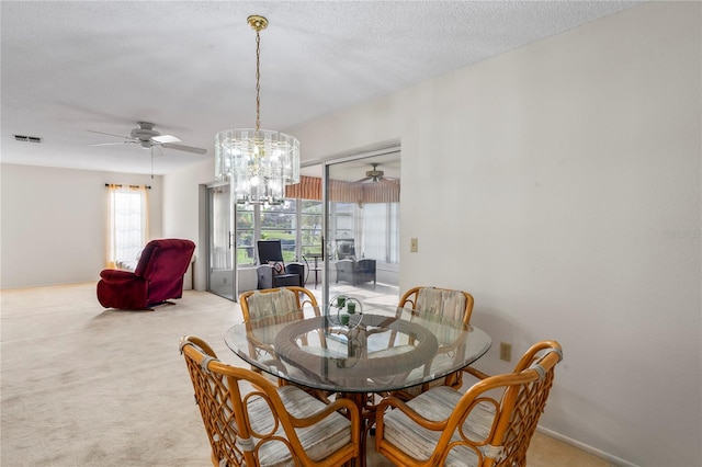 dining area featuring a textured ceiling, ceiling fan with notable chandelier, and light carpet