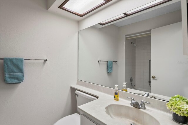 bathroom with tiled shower, vanity, and toilet