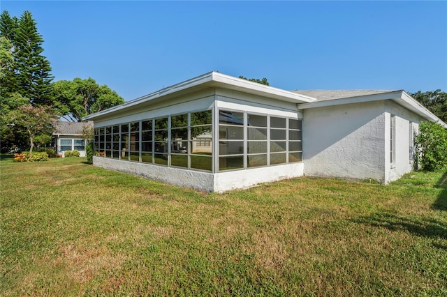 view of property exterior featuring a sunroom and a yard