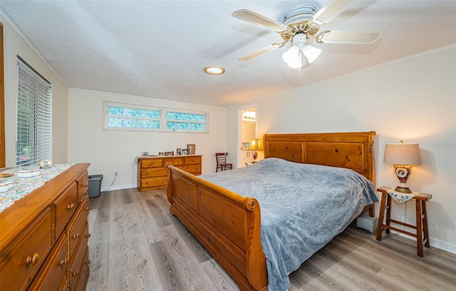 bedroom with ceiling fan, a textured ceiling, and light hardwood / wood-style flooring