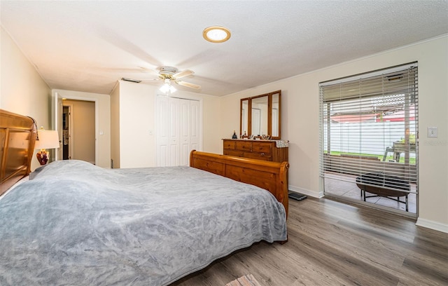 bedroom with a textured ceiling, hardwood / wood-style floors, ceiling fan, and a closet