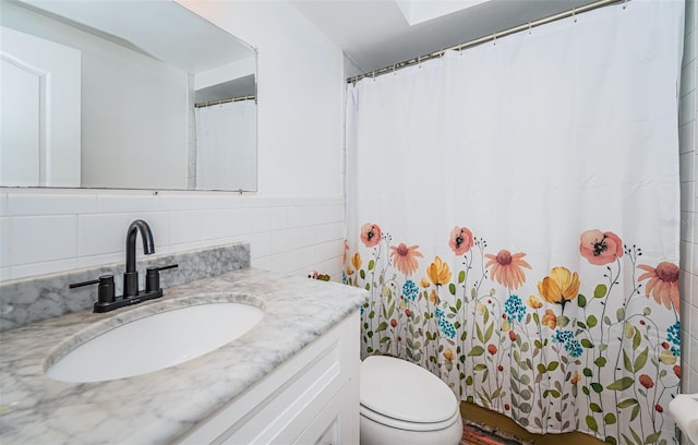 bathroom featuring vanity, toilet, tile walls, and tasteful backsplash