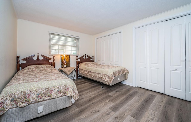 bedroom with hardwood / wood-style floors, a textured ceiling, and multiple closets