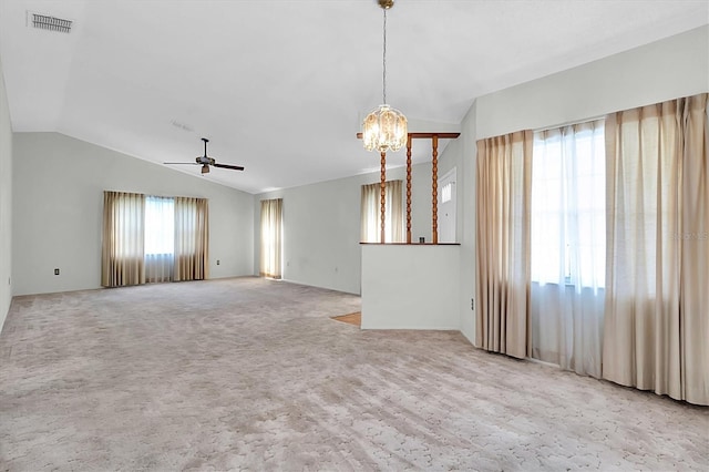 carpeted spare room with visible vents, vaulted ceiling, and ceiling fan with notable chandelier