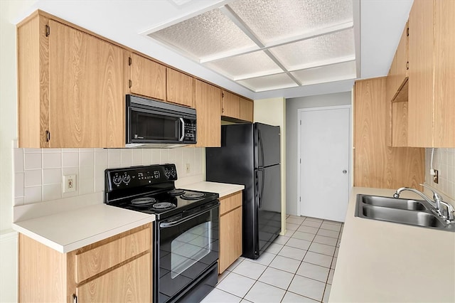 kitchen with light tile patterned floors, tasteful backsplash, light countertops, a sink, and black appliances