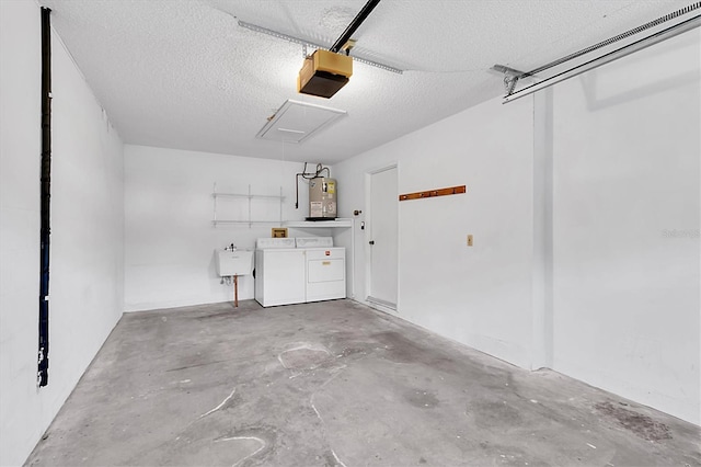 garage with water heater, a garage door opener, a sink, and washer and dryer