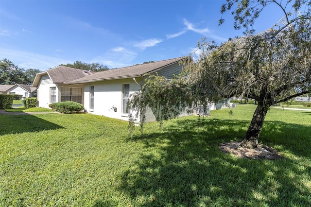 view of side of home with a yard and stucco siding