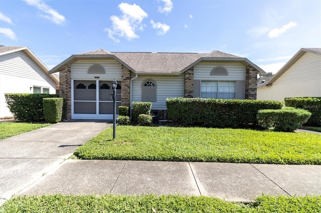 single story home featuring driveway, an attached garage, a front lawn, and brick siding