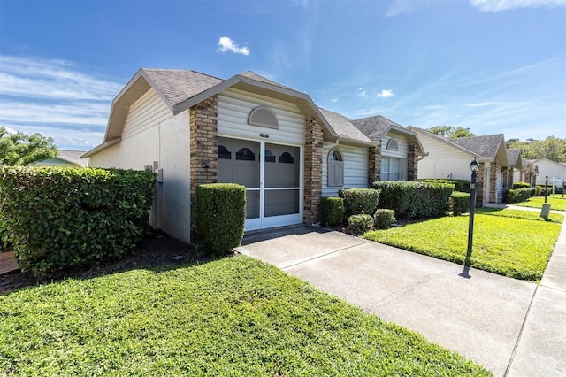 view of front of house featuring driveway, roof with shingles, an attached garage, a front lawn, and stucco siding