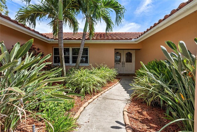 2044 Montana Ave NE, Saint Petersburg, FL 33703 - entrance to property with french doors, a tile roof, and stucco siding