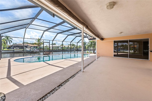 view of pool with a lanai, a water view, and a patio