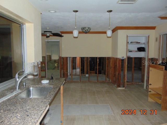 kitchen with pendant lighting, sink, ceiling fan, light stone countertops, and light hardwood / wood-style floors