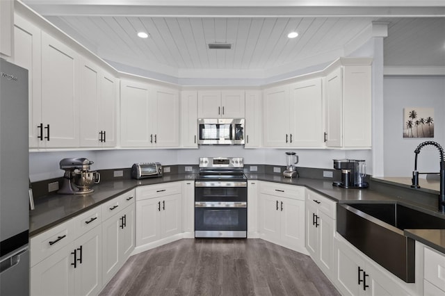 kitchen featuring dark wood-type flooring, white cabinets, appliances with stainless steel finishes, wooden ceiling, and sink