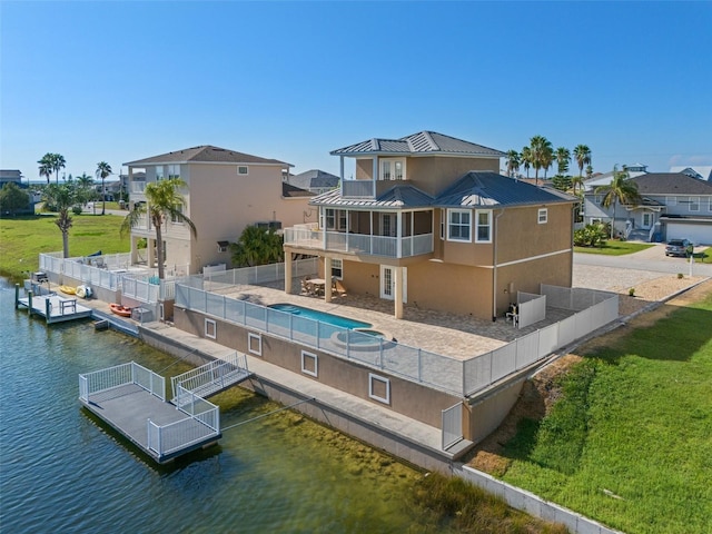 rear view of property featuring a balcony, a patio area, a fenced in pool, a water view, and a lawn