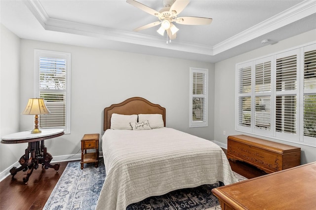 bedroom featuring dark hardwood / wood-style flooring, ornamental molding, a tray ceiling, and ceiling fan