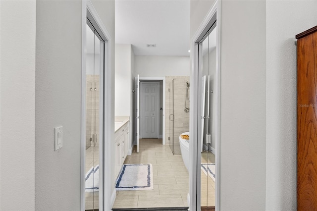 bathroom with a shower with door, vanity, and tile patterned flooring