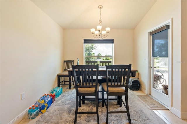 dining area featuring lofted ceiling, light tile patterned flooring, and a notable chandelier