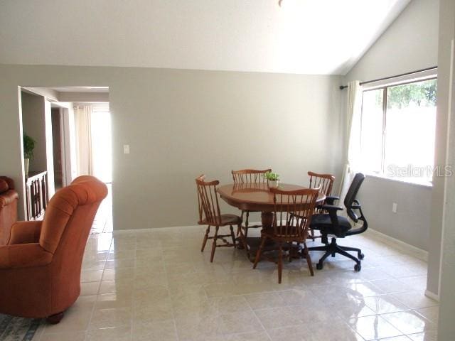 dining room with lofted ceiling and light tile patterned flooring