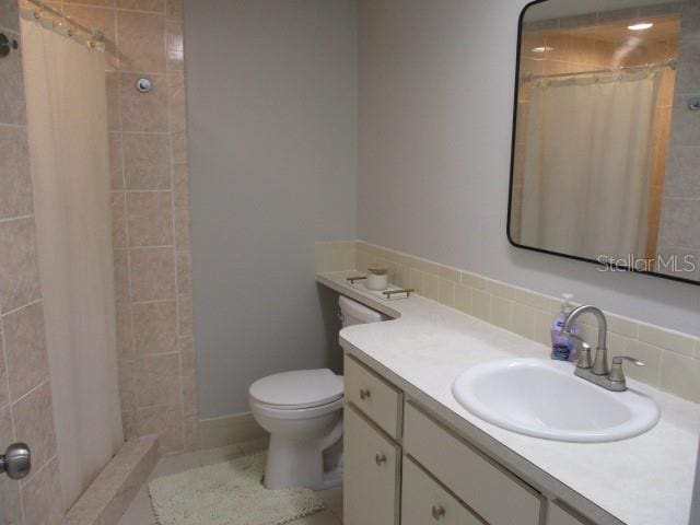 bathroom featuring toilet, tasteful backsplash, a shower with curtain, and vanity