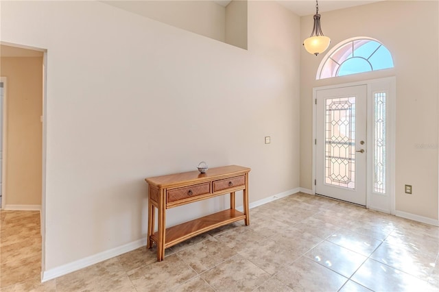 entrance foyer featuring light tile patterned floors, a towering ceiling, and baseboards