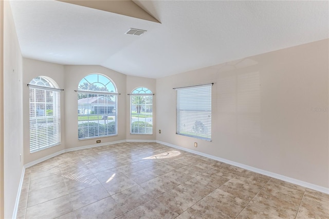 empty room featuring baseboards, visible vents, vaulted ceiling, and light tile patterned floors