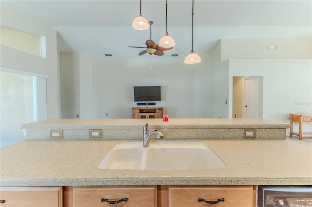 kitchen featuring ceiling fan, sink, light stone countertops, and decorative light fixtures