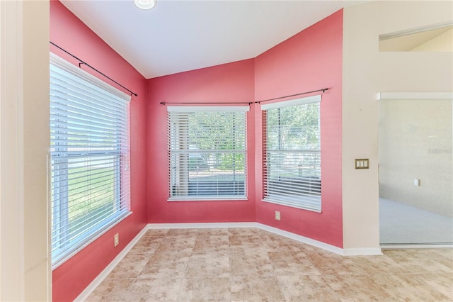 tiled spare room featuring vaulted ceiling