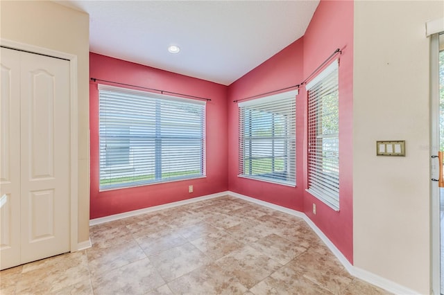 unfurnished room with baseboards, vaulted ceiling, and tile patterned floors