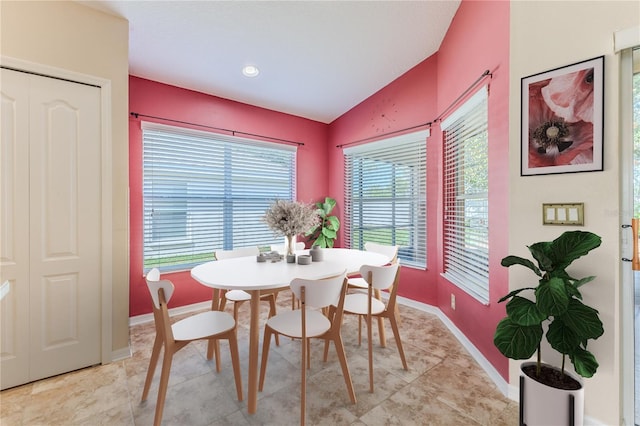 dining room featuring baseboards, lofted ceiling, and light tile patterned flooring