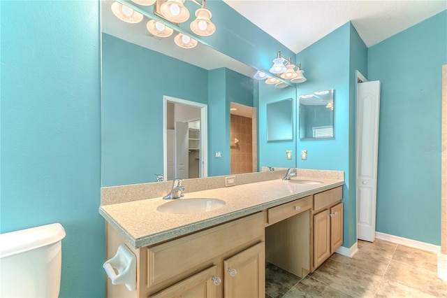 full bath featuring baseboards, double vanity, a sink, and toilet