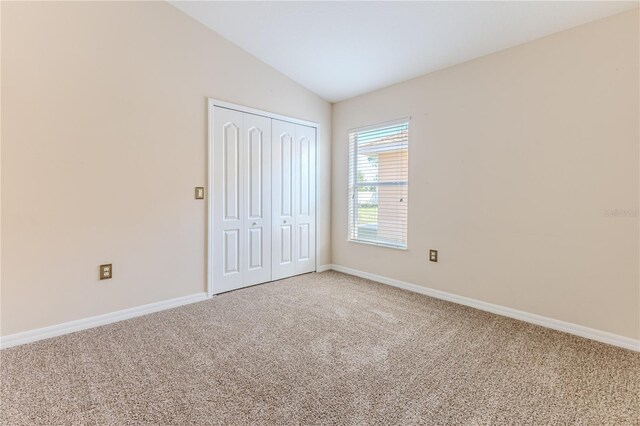 unfurnished bedroom with carpet flooring, a closet, and lofted ceiling