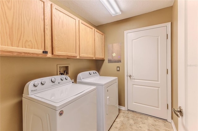 clothes washing area featuring washing machine and clothes dryer, cabinet space, and a textured ceiling