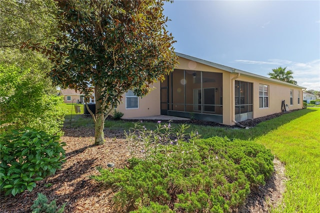 back of property featuring a sunroom, stucco siding, and a yard