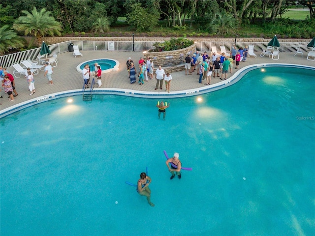 community pool featuring fence, a hot tub, and a patio area