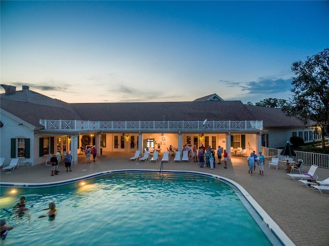 pool at dusk featuring a community pool and a patio area