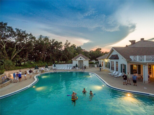 pool at dusk with a patio area