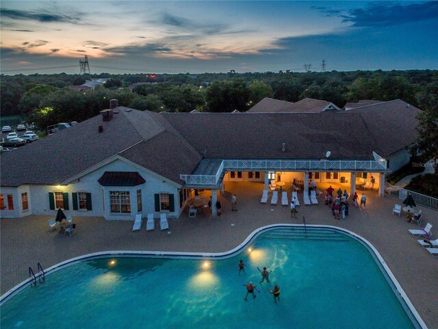 pool at dusk featuring a patio