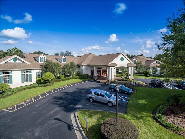 view of front of home with stucco siding, uncovered parking, and a front yard