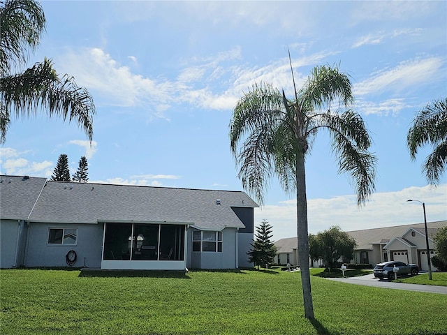 rear view of property with a lawn, a sunroom, and stucco siding