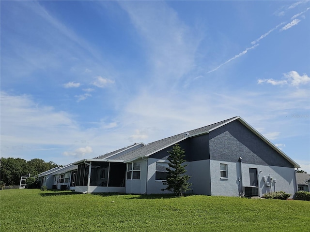 back of house with cooling unit, a sunroom, and a lawn