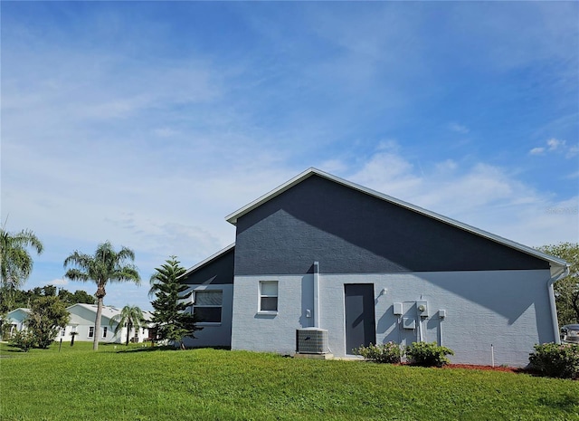 back of house featuring central air condition unit, a yard, and stucco siding