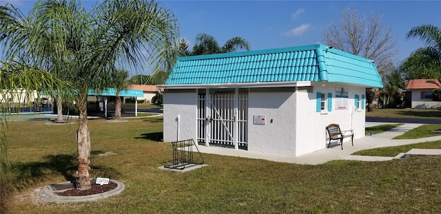 rear view of property featuring stucco siding, mansard roof, and a yard